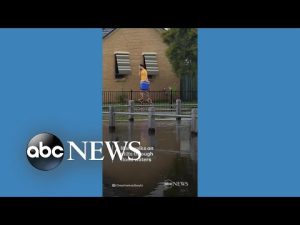 Read more about the article Man walks on stilts through flood waters